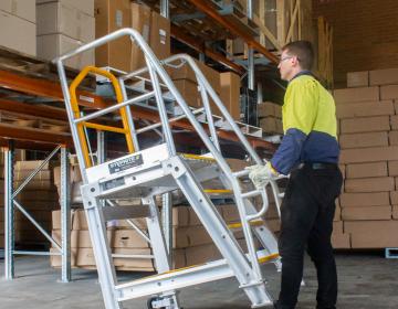 man rolling access ladder up to shelving